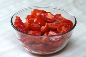 Старайтесь выбирать спелые и без вмятин помидоры. Промойте овощ и нарежьте дольками, предварительно удалив плодоножку.