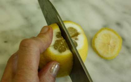 Апельсины под проточной водой промыть. Ножом разрезать фрукты на четыре части. Косточки можно оставить. Затем переложить дольки апельсина в емкость.