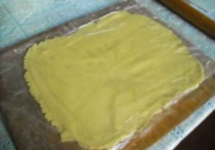 Взять два куска плотной полиэтиленовой пленки.  Разослать на столе  кусок пленки, сверху на него положим тесто и накроем вторым куском. Раскатать тесто скалкой в прямоугольный пласт. Через пленку это будет  легко сделать.