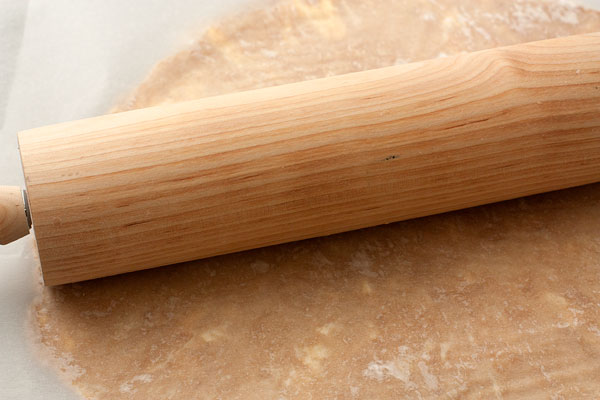 Раскатайте тесто между двумя листами бумаги для выпечки в пласт толщиной 5 мм, выложите им форму для выпечки, наколите вилкой и уберите в морозилку на 15-20 минут, чтобы оно как следует охладилось.