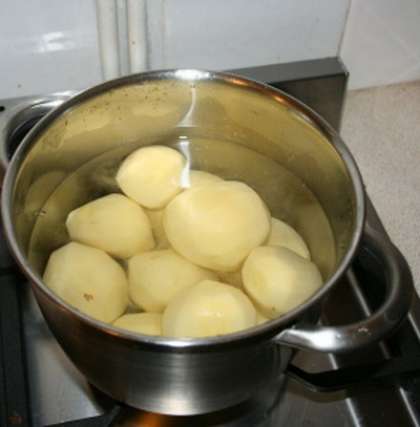 Тщательно промыть в холодной воде картофель. Клубни почистить. Набрать в кастрюлю холодной воды и поставить на огонь. Когда вода закипит посолить и отправить туда картофель. Варить до готовности.
