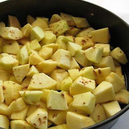 Специальную форму для выпечки смажьте растительным маслом и выложите равномерно яблоки.