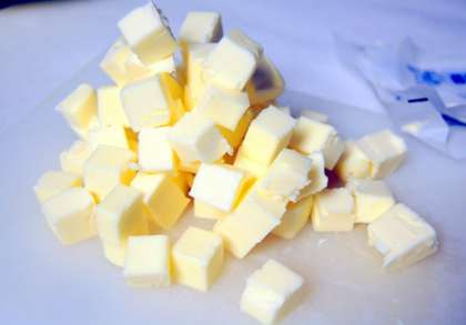Охлажденное сливочное масло выложить на разделочную доску и нарезать ножом небольшими  кубиками. Снова поставим масло в холодильник.