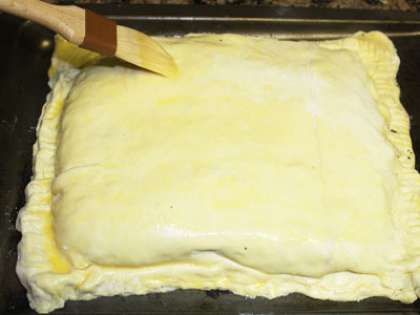 Специальной кистью смажьте верх пирога слегка взбитым яйцом. Духовку разогрейте до 230 градусов и выпекайте пирог полчаса. Готовый пирог достаньте из духовки и пусть он немного остынет.