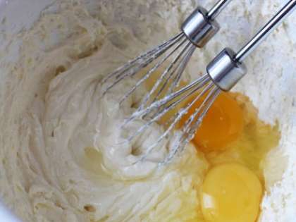 В глубокую миску, вбить два куриных яйца, добавить сахар и ваниль. Затем взбиваем до растворения сахара миксером. Затем сюда же ввести пшеничную муку, творог, картофельный крахмал и смешать.
