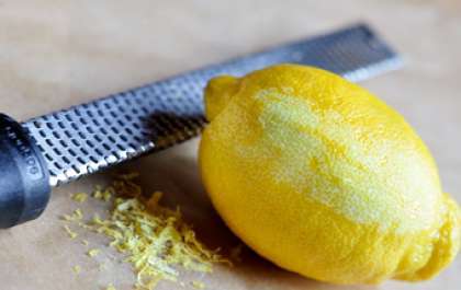 Обдайте лимон кипятком, чтоб ушла вся горечь из цитруса, просушите кухонным полотенцем и натрите цедру на мелкой терке. Лимон без цедры разрежьте пополам и отожмите из него сок в отдельную чашку.