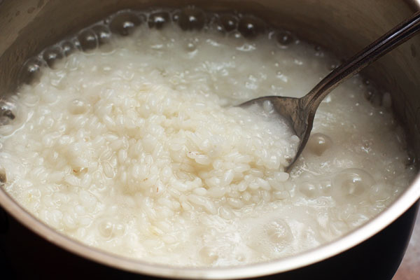 Круглозерный рис, не промывая, залейте небольшим количеством воды (примерно стакан, чтобы только покрыть рис на 1 см), поставьте на огонь и готовьте на среднем огне, пока вода не впитается.  Помешивайте рис, чтобы он не подгорал.