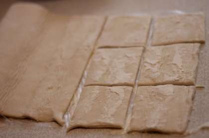 Разморозьте слоеное тесто, или по желанию приготовьте его самостоятельно по своему рецепту. Рецепт слоеного теста всегда найдется у каждой хорошей хозяйки. Тонко раскатайте тесто и порежьте его на квадраты.