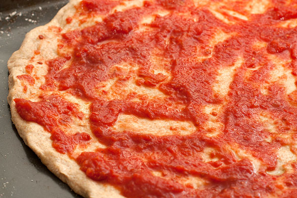 Соус для пиццы равномерно распределите по лепешке.