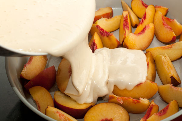 Вылейте тесто на персики.