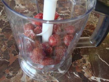 Клубнику выкладываем в блендер. Можно использовать как замороженную ягоду, так и свежую. Размельчаем ягоду до состояния пюре и всыпаем немного сахарной пудры, все снова перемешиваем в блендере.