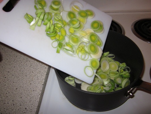 Отрежьте темно-зеленую часть лука порея. Для супа понадобится лишь белая и светло-зеленая часть. Режем лук порей и тушим в той же кастрюле, где жарился бекон, 5-10 минут, добавив 1 ст. ложку масла.