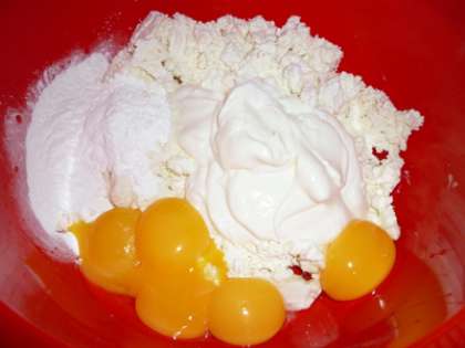 Перед приготовлением яйца достаньте из холодильника за час. Отделите от пяти яиц желтки. В емкости смешайте мягкий и вкусный творог с желтками, к ним добавьте сметану, ванилин и крахмал.