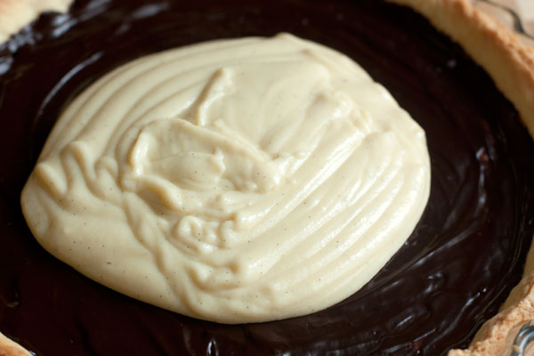 Когда шоколад полностью застынет, выложите холодный крем на основу и разровняйте.