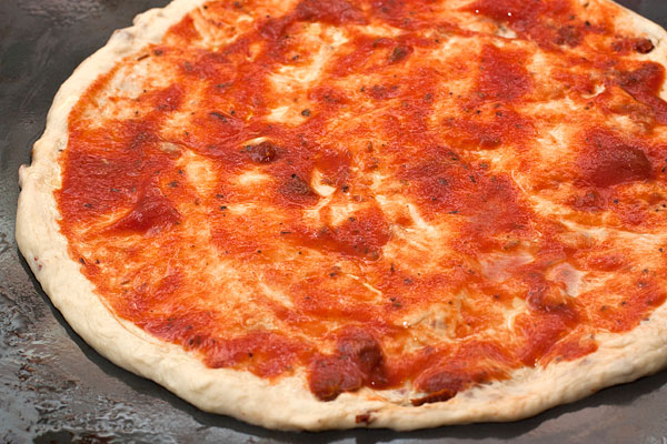 Равномерно смажьте основу для пиццы соусом для пиццы.