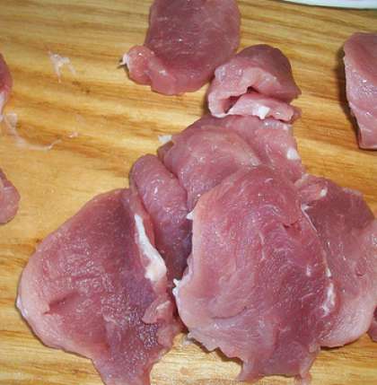 Помойте мясо, для этого блюда лучше брать свинину. Это – нежное, сочное мясо, оно хорошо подходит к картошке. Нарежьте его на небольшие кусочки, пересыпьте свежей зеленью, дайте немного соли, немного перцу.