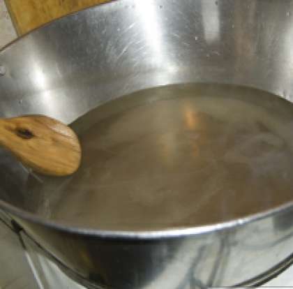 Возьмите посуду для варки варенья, залейте воду и закипятите ее на среднем огне. Затем положите сахар и растворите его, помешивая  ложкой или деревянной лопаткой. Потом засыпьте шишки сосны в емкость с сиропом.