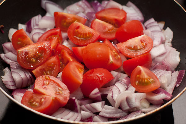К луку добавьте крупно нарезанные помидоры (на фото  сорт чуть крупнее черри).