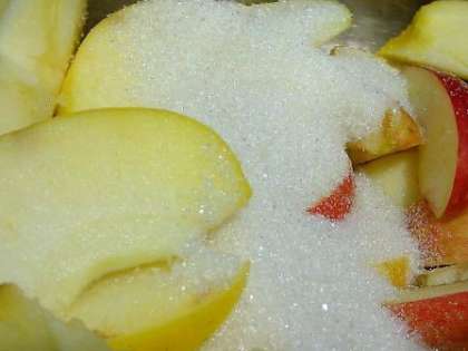 Далее нужно положить в кастрюлю, в которой вы собираетесь варить яблочный компот. Смешайте там нарезанные яблоки с сахаром.