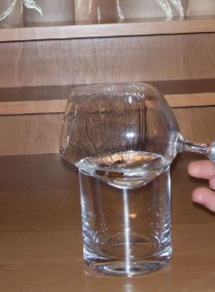 Смочите все грани бокала ликером, аккуратно провернув его несколько раз. Потом поставьте коньячный бокал на стакан для виски, наклонив его (т.е. боком).
