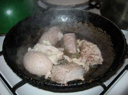 Один за другим обваривайте кусочки мяса и перебрасывайте на сковороду. Затем прибавьте огонь под сковородой. Накройте крышкой. Жарьте 12-15 минут. А пока жарится мясо порежьте репчатый лук тонкими кольцами.