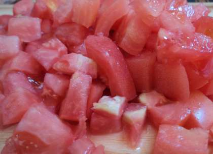 Потом займитесь помидорами. Опустите их на минуту в кипяток, обмойте водой. Далее снимите кожуру с них, и порежьте мелкими квадратиками.