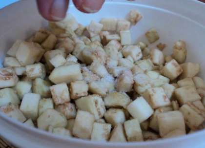 Баклажаны помойте. Обсушенные овощи следует очистить и порезать кубиками (мелкими). Затем положите баклажаны в миску. Смешайте порезанные баклажаны с солью. Оставьте их так минут на 20-25. Это нужно для того, чтобы баклажаны перестали быть горькими.