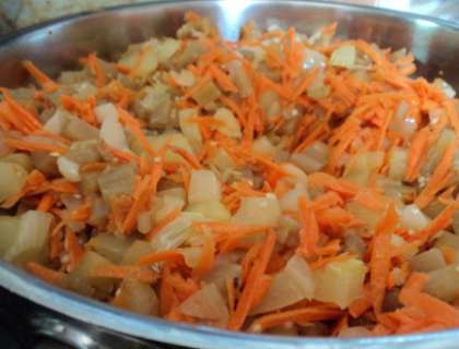 Затем одновременно добавьте лук и морковь. Еще десять минут потушите овощи на медленном огне.