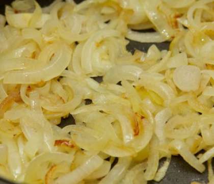 На сковороду налейте масла растительного. Поставьте ее и разогрейте. Выложите порезанный полукольцами лук, обжарьте его слегка, а затем добавьте капусту.