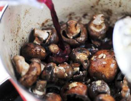 Добавьте грибы и готовьте ещё 2 минуты. Влейте консоме и вино. В случае необходимости можете добавить дополнительно немного воды. Затем добавьте по вкусу соль и перец, перемешайте. Доведите до кипения.