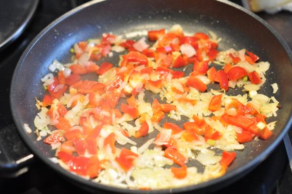 На среднем огне обжарьте мелко порубленный лук в течение 5 минут, добавьте нарезанный мелкими кубиками красный перец, соль и жарьте еще 5 минут. Добавьте мелко нарезанный чеснок.