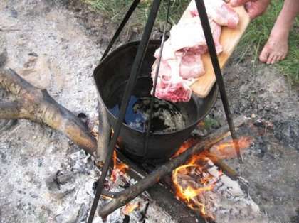 Установите ведро (или котел) над огнем, налейте в него холодную воду, и опустите туда разделанную курицу.