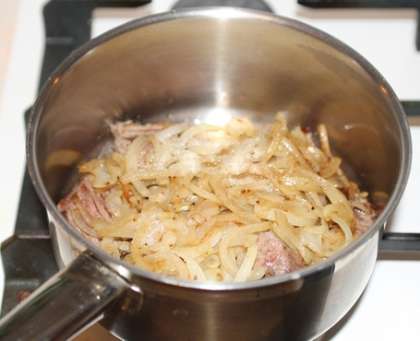 Выложите мясо на дно кастрюли, и засыпьте его слегка обжаренным луком.