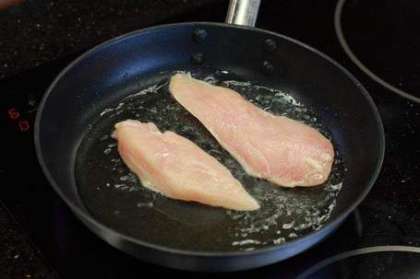 Разогрейте сковороду, влейте в неё оливковое масло, и обжарьте в нем куриные грудки так, чтобы мясо слегка поджарилось.