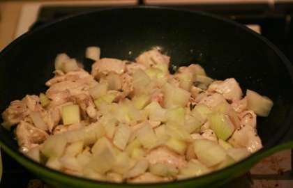 Выложите лук в сковороду к куриному филе. Тушите ещё 5 минут.