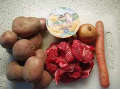 Чтобы приготовить тушеную картошку с мясом в мультиварке, приготовьте свинину или говядину, картошку, сметану, репчатый лук, морковь, чеснок, масло для жарки, соль, лавровый лист и перец горошком.