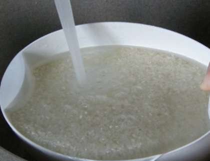 Возьмите для каши лучше круглый рис. Он быстро вариться, а также он богат крахмалом. Промойте рисовую крупу. Мойте рис в кастрюле или миске столько раз, чтобы вода стала как можно прозрачнее (обычно это 5-7 сливаний).