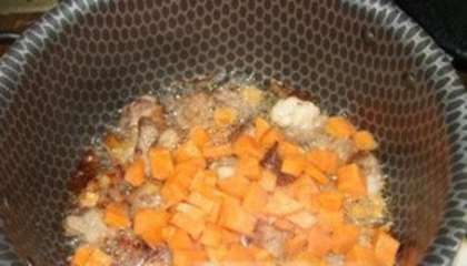 Нарежьте кубиками морковь и добавьте в казан к мясу.