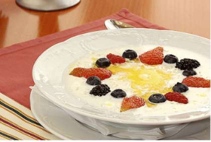 Налейте готовую манную кашу в тарелки. Налейте масла. Затем выложите ягоды в виде рисунка. Подавайте на стол. 