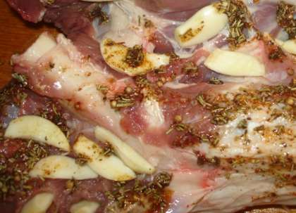 Возьмите костяшку баранью, которую вы приготовили. Надрежьте мясо вдоль косточки. Разверните его. Затем нашпигуйте все мясо изнутри чесноком, а также натрите смесью оливкового масла и специй.