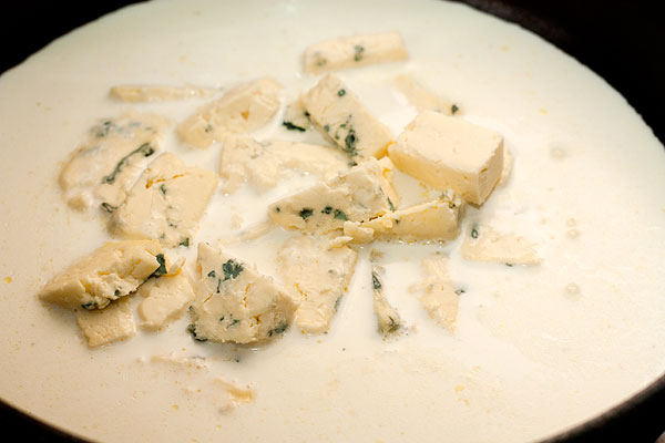 В сковороде с толстым дном растопите сыр вместе со сливками.