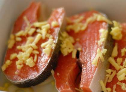 Возьмите форму для запекания (стеклянную или керамическую) с толстыми краями. Из  части морковки и лука сделайте овощную подушку. Выложите приготовленные стейки красной рыбы. Посыпьте кусочками имбиря.