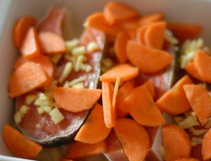 Потом покройте рыбу снова морковкой, порезанной кусочками, добавьте немного лука сверху.
