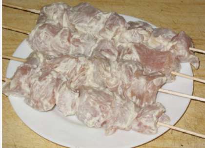 После того, как прошло время мариновки мяса, достаньте кусочки курицы их холодильника. Потом возьмите предварительно вымоченные деревянные шпажки для шашлыков и нанизывайте мясо на них, чередуя с овощами.