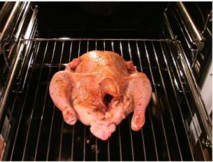 Разогрейте духовку. Положите курицу на решетку. Температура запекания должна быть от 180°С до 200°С. Жарьте курицу где-то полтора-два часа. А, чтобы жир не горел, налейте в противень немного воды и поставьте его вниз, под курицу. Проткните ее ножом, если сок светлый – курица готова, а если с кровью, тогда нет.