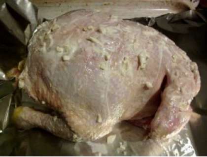 На противень застелите кусок фольги. В ней курица сохранит свою форму. Смажьте тушку соусом со сметаны и чеснока.