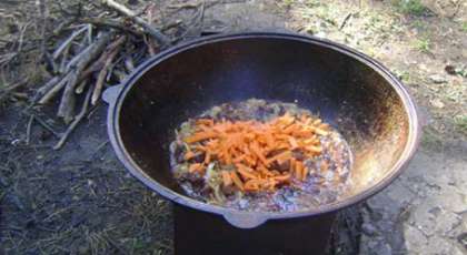 Режем морковь соломкой и добавляем ее в казан, жарим до мягкого состояния.
