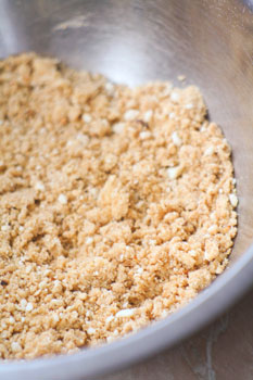 Печенье измельчаем в блендере, орехи мелко нарезаем. Сливочное масло растапливаем и смешиваем с печеньем и орехами.
