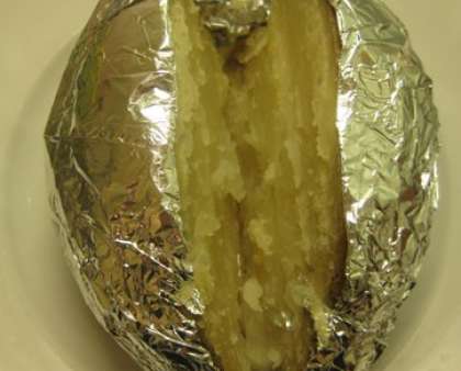 Готовый картофель вытащите из духового шкафа и выложите прямо в фольге на порционные тарелки. Разрежьте затем каждый клубень картошки прямо с фольгой, но не до конца, можно посолить разрез.