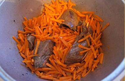 Кладем к поджаренному мясу заранее очищенную и порезанную маленькими брусочками морковь, жарим смесь овощей и мяса ещё примерно 10 минут.